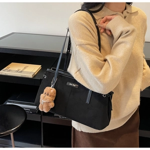 Détail d'un sac cabas noir minimaliste avec texture mate et charme d'ours en peluche