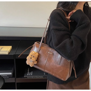 Détail d'un sac à bandoulière en cuir vintage marron avec breloque ours en peluche