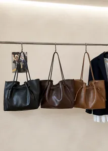 Τρεις μινιμαλιστικές μεγάλες τσάντες tote σε μαύρο και καφέ κρεμασμένες σε βάση