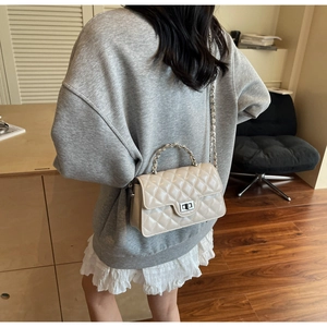 Détail du sac à rabat matelassé beige avec poignée courte en métal et bandoulière