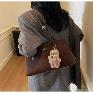 Détail du sac à bandoulière en daim marron foncé avec charm ours et sangle