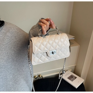 Détail du sac matelassé crème avec bandoulière chaîne argentée et fermoir pivotant
