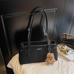 Détail du sac à bandoulière noir mat avec boucle en métal et pendentif ours marron