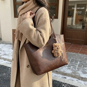 Vintage large brown leather tote bag for women with plush bear charm and long shoulder strap