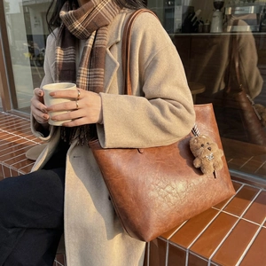 Vintage brown large capacity tote bag with bear charm shown in an autumn fashion scene