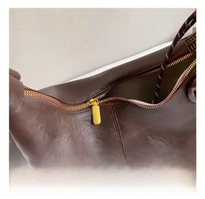 Detailed close-up of dark brown leather texture and golden metal zipper hardware