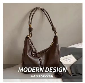 Macro detail of dark brown soft leather hobo bag with knotted strap and gold hardware