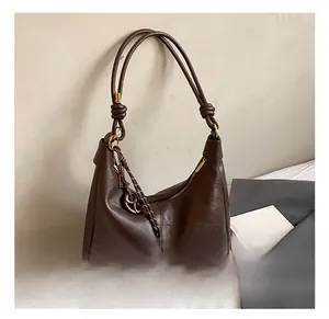 Macro detail of dark brown soft leather hobo bag with knotted strap and gold hardware