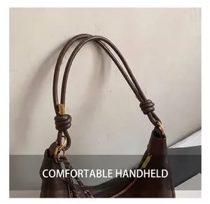 Detail of dark brown leather tote with dual rope-style straps and gold ring hardware