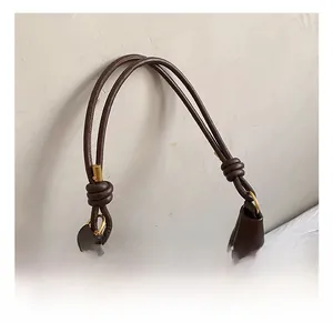 Detail of dark brown leather tote with dual rope-style straps and gold ring hardware