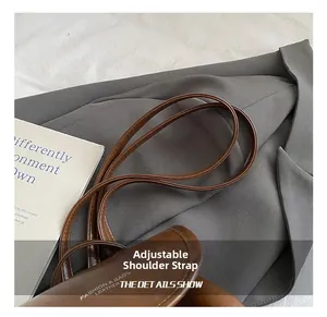 Λεπτομέρεια του ρυθμιζόμενου δερμάτινου ιμάντα και λευκό λογότυπο σε καφέ σακίδιο