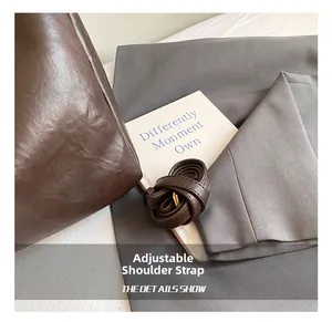 Detail of adjustable leather shoulder strap with gold buckle on dark brown tote bag