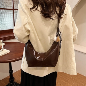 Deep brown crescent shoulder bag with glossy finish and baseball glove charm