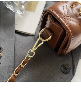 Close-up of golden rotating hook and chain strap on brown quilted crossbody bag