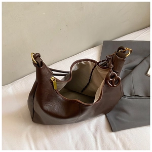 Detailed view of dark brown leather crescent bag with golden zipper and ring buckle