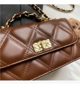 Close-up of brown quilted leather bag with golden chain and textured twist lock detail