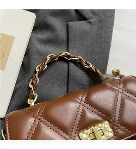 Detail of brown quilted leather bag featuring gold chain handle and metal lock