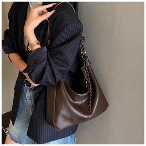Detail of soft dark brown leather tote with decorative knotted strap and woven pendant