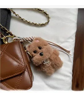 Detailed close-up of a brown plush dog charm with a Top Dog bone tag on a quilted bag