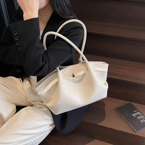 White lychee leather underarm bag with gold buckle on elegant model on wooden stairs