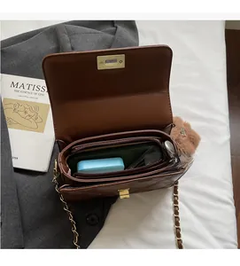 Interior view of brown quilted crossbody bag showing multiple compartments and gold clasp