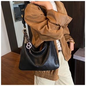Detail view of black vintage leather tote bag on model showing soft grain texture