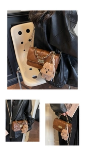 Close-up of brown quilted crossbody bag with gold chain and plush bear charm detail