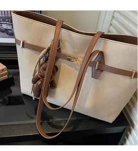 Canvas tote bag detail showing leather shoulder straps and cute plush bear charm decoration