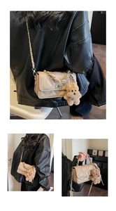 Detail of beige quilted chain bag featuring a gold lock and a brown plush bear charm