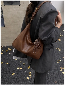 Detail of dark brown leather hobo bag with unique knot shoulder strap and charms