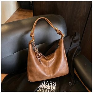 Detail of a brown hobo bag with woven knot strap and textured faux leather finish