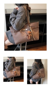 Detail of coffee brown tote bag with decorative belts, metal buckles and plush bear charm