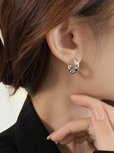Close-up of silver textured lava hoop earrings on model featuring minimalist C-shape design