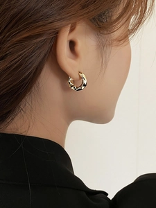 Close-up of gold irregular hammered hoop earrings with textured metal surface on ear