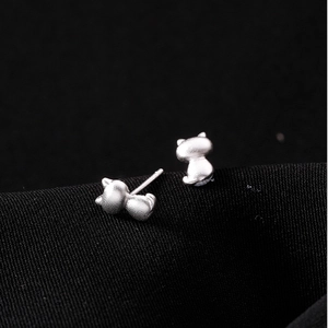 Macro view of matte S925 sterling silver cat stud earrings on black textured fabric