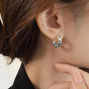 Silver fluid texture hoop earrings with modern irregular metallic design on model