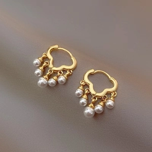 Elegant gold cloud drop earrings with graduated pearls on a textured background