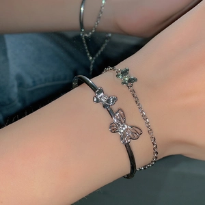 Close-up of double-layered silver butterfly bracelet with tassel detail on woman's wrist