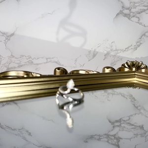 Detailed view of a silver snake ring with white pavé stones and green crystal eyes