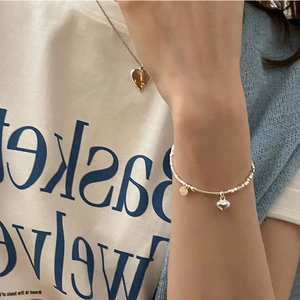 Dettaglio del bracciale con cuore in argento S925 e collana ambra su modella