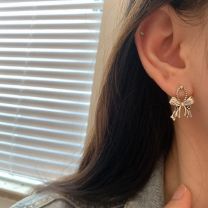 Detail of vintage S925 silver bow earrings worn against a soft indoor setting