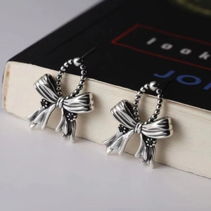 Macro shot of vintage S925 silver bow earrings with black gemstone insets and aged finish