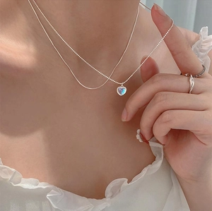 Detail of s925 silver double-layered heart necklace with moonstone pendant on a model