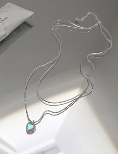 Detail of s925 silver double-layered heart necklace with glowing moonstone gemstone