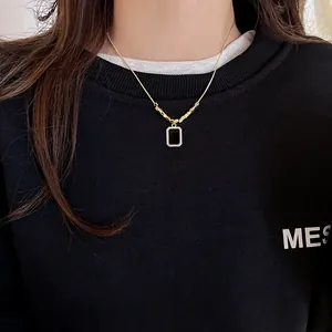Gros plan d'un collier rectangulaire noir en or 18 carats sur un pull noir