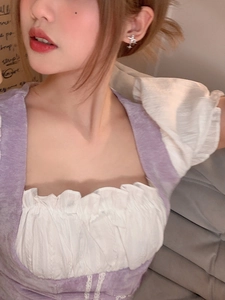 Close-up of S925 silver cross earrings with dangling fringe on a model wearing purple top