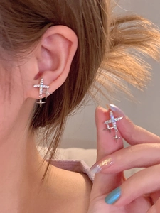 Detail of S925 silver cross stud earring with shimmering crystals and tassel pendant drop