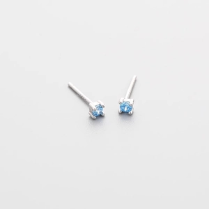 Macro view of S925 silver stud earrings featuring blue zircon in a four-prong setting