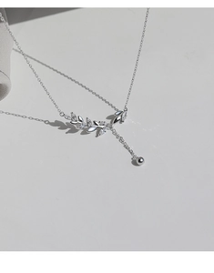 Detailed view of silver olive leaf pendant with sparkling marquise-cut zircon and tassel