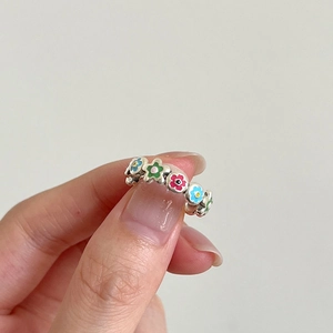 Handheld view of a silver S925 ring featuring colorful enamel floral patterns and a cute design
